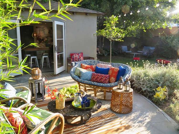 شرفة حديقة على الطراز البوهيمي من القش ، مقاعد معدنية ، طاولة قهوة ، فوانيس شموع