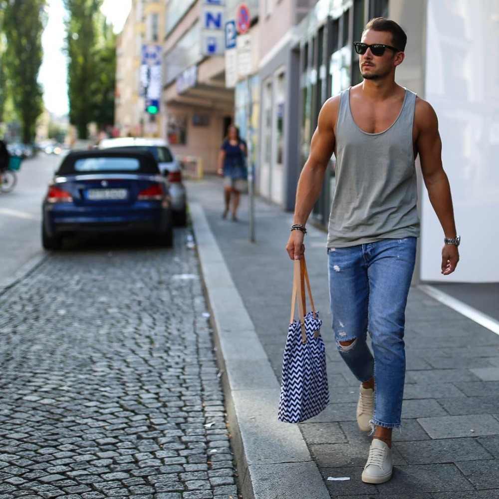 جينز للرجال في الثمانينيات من القرن الماضي يرتدون ملابس الشارع مع الأحذية الرياضية وحقيبة النظارات الشمسية