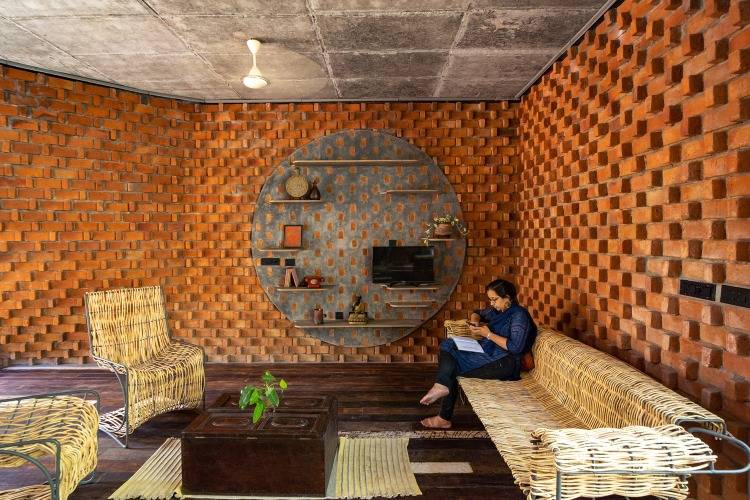 امرأة تجلس على أثاث معاد تدويره في غرفة المعيشة مع جدار من الطوب مزخرف بالداخل