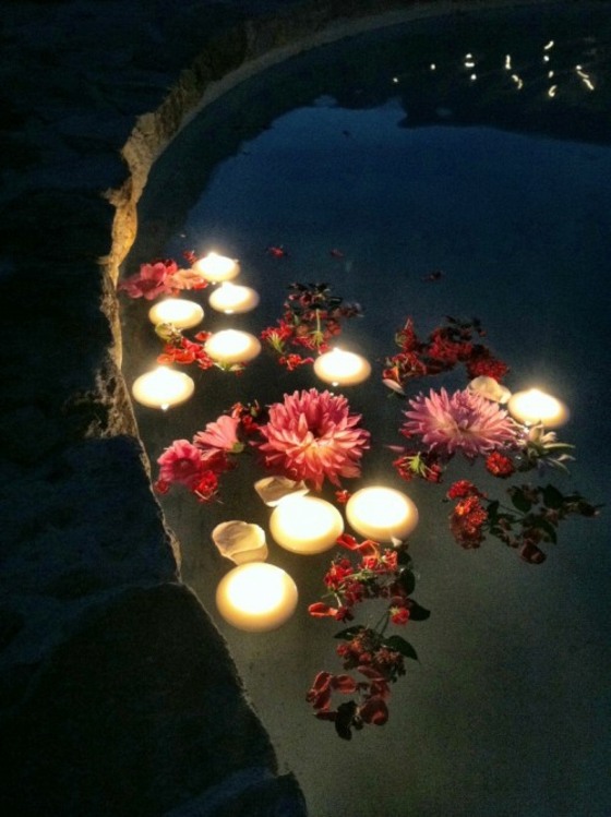 زهور في الماء في ضوء المساء مع شموع مضاءة