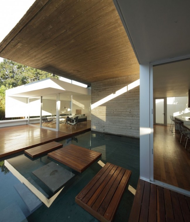 منزل حديث سقف مسطح سطح خشبي يخطو الحجارة بركة المياه الجدار الزجاجي الداخلي