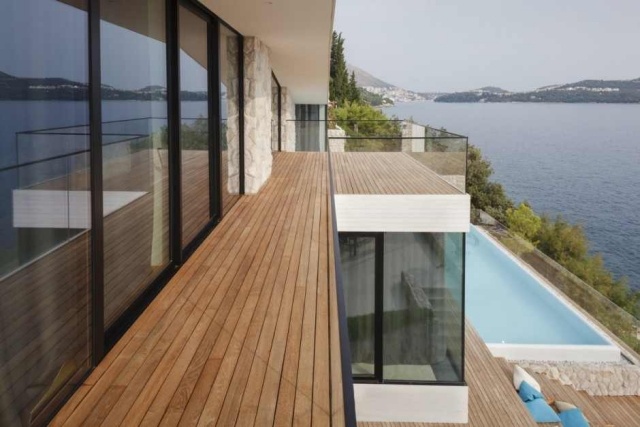 منزل حديث بواجهة زجاجية وشرفة مطلة على البحر