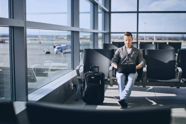 رجل يحمل كمبيوتر محمول ينتظر في المطار