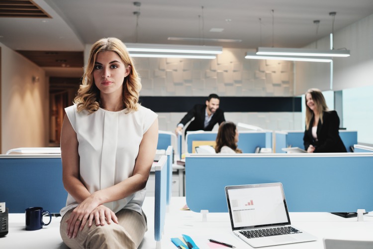 امرأة تجلس بمفردها على المكتب في المكتب بجوار زملائها
