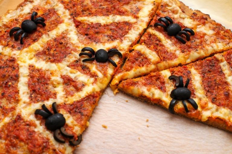 بيتزا الهالوين مع شبكة عنكبوت مصنوعة من الجبن والعناكب المصنوعة من الزيتون