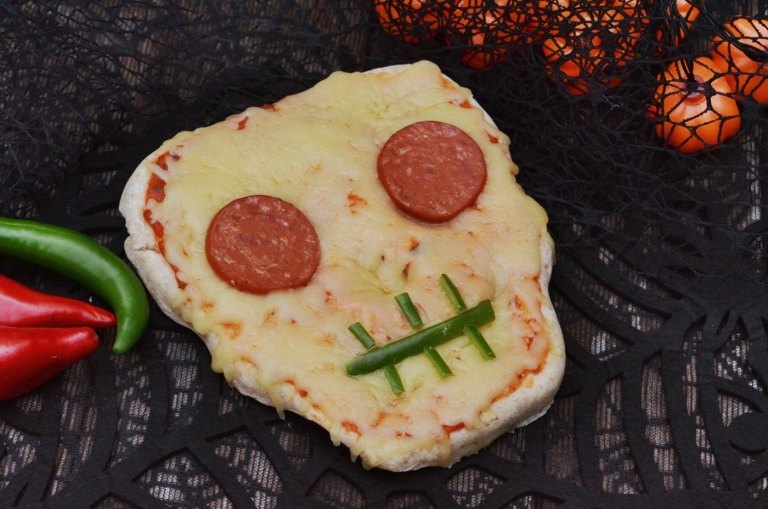 بيتزا الهالوين المضحكة على شكل جمجمة مع سلامي ، بابريكا وجبنة