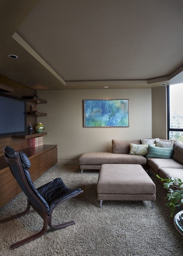 ادمج السينما المنزلية في غرفة المعيشة مع أرفف الحائط الخشبية ذات الأريكة الركنية