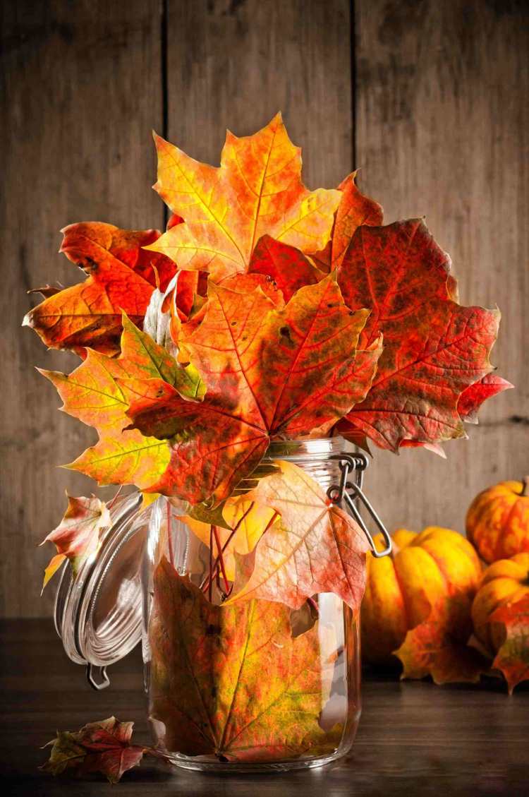 زينة الخريف في جرة ميسون أوراق الخريف بدرجات اللون الأحمر والبرتقالي. jpg