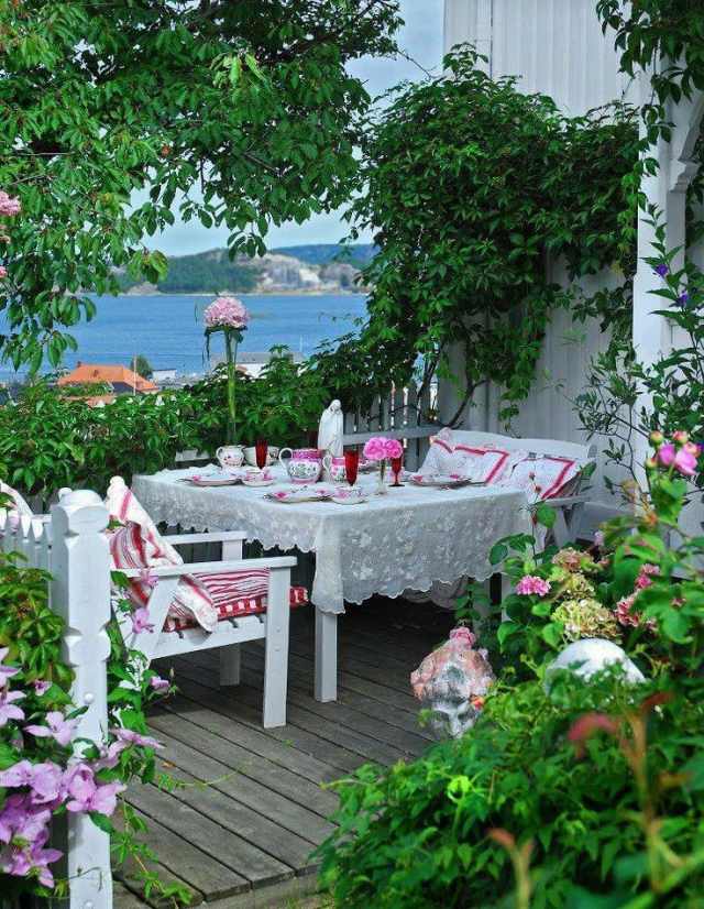 شرفة البحر الأبيض المتوسط ​​مع إطلالة على البحر كراسي بيضاء مفرش المائدة - نمط الأزهار