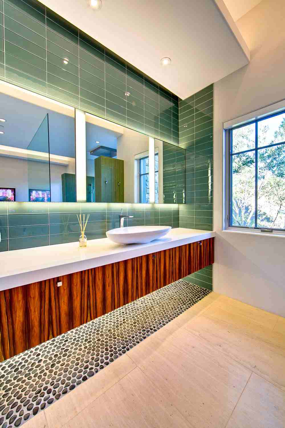 تصميم حمام ملون ببلاط أخضر وخشب وحصى على الأرض