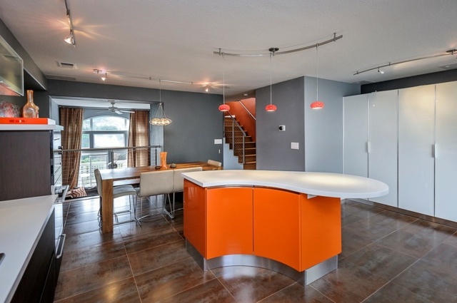 جزيرة طبخ نصف دائرية برتقالية اللون مدمجة في ركن الأجهزة المطبخ من الخشب الداكن