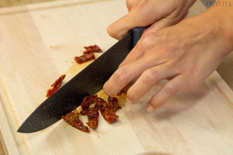 يقطع سكين المطبخ الطماطم المجففة إلى قطع