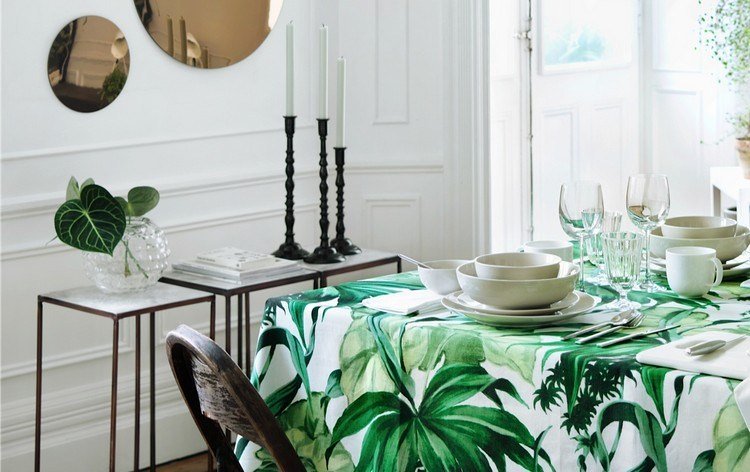 مفرش طاولة منقوش بأوراق خضراء ومجموعة أطباق بيضاء