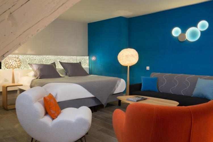 لون الحائط-فيروزي-غرفة نوم-سرير-جلوس-تنجيد-خمسينيات-غير مباشر-إضاءة-برتقالي