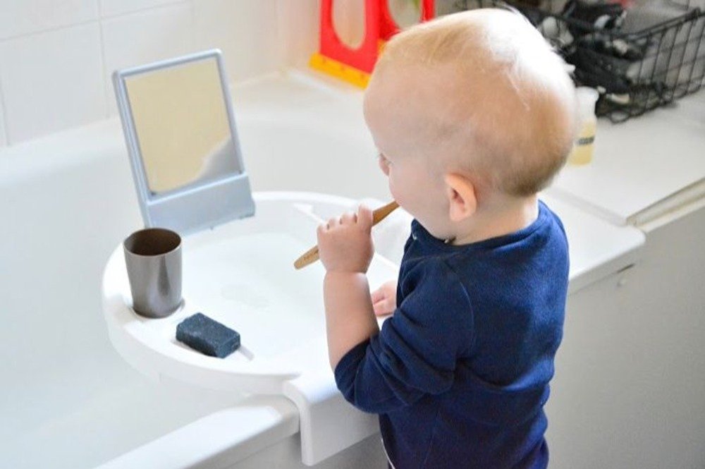 طفل صغير يفرش أسنانه بأسلوب مونتيسوري يبني مغسلة للأطفال بأنفسهم