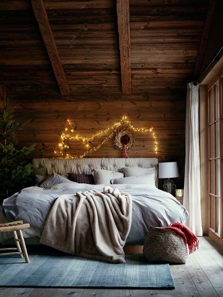 زينة عيد الميلاد في غرفة النوم مع أضواء خرافية فوق اللوح الأمامي للسرير وشجرة عيد الميلاد