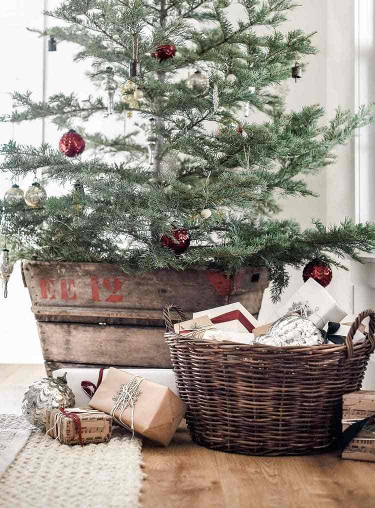 ترتيب شجرة عيد الميلاد في صندوق خشبي ، وملء الهدايا في سلة