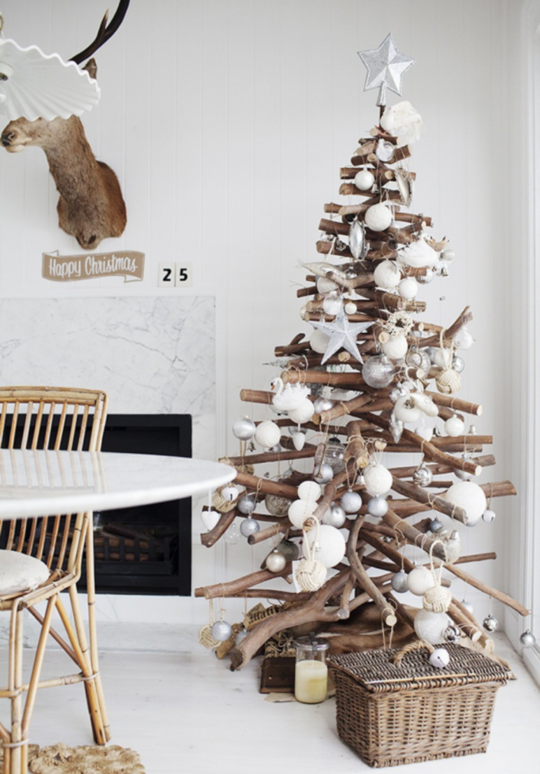 شجرة عيد الميلاد مصنوعة من الخشب مع فروع شجرة مكدسة وزينة عيد الميلاد البيضاء بأسلوب ريفي