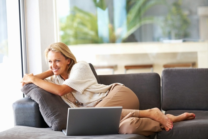 الدفء والراحة في الكمبيوتر المحمول أريكة امرأة المنزل