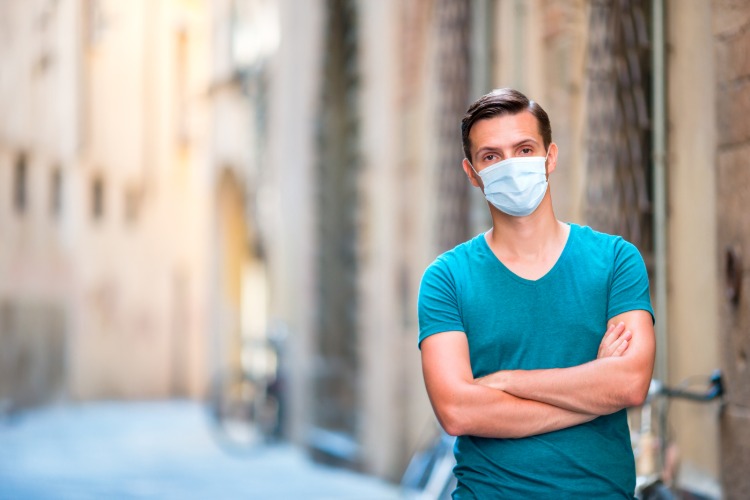 رجل يرتدي قناعًا للوجه يقف في الشارع بإيطاليا أثناء جائحة فيروس كورونا